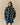 A person wearing a forest green Warm & Wonderful Sheep Sherpa Jacket patterned with small white sheep.
