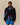 A person wears the Paddington Sherpa Jacket Navy by Rowing Blazers x Paddington™ with blue athletic shorts, standing against a beige background.