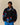 Wearing the Paddington Sherpa Jacket Navy by Rowing Blazers x Paddington™, featuring colorful cartoon bears, a person stands against a beige background with hands in pockets.