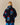 A person with blonde hair faces away, wearing the Paddington Sherpa Jacket Navy by Rowing Blazers x Paddington™, featuring a Paddington bear pattern. The background is plain beige.
