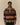 A man wearing a Rowing Blazers Fair Isle Clark Sherpa Multi-Color fleece pullover with a multicolored, Fair Isle pattern and a snap-button mock neck.