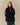 A person wearing a navy blue Rowing Blazers Clark Sherpa Navy pullover with a purple snap-button placket, zippered side pockets, and logo patches on the chest and sleeve.