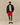 A man wears a Rowing Blazers x Paddington™ Tuxedo Paddington Classic Sherpa Black full-zip jacket with repeating bear motifs, a white t-shirt, red mesh shorts, white socks, and dark brown loafers.