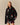 A person wearing a black full-zip Rowing Blazers x Paddington™ Tuxedo Paddington Classic Sherpa Black jacket patterned with illustrated bears wearing red hats.