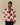 A man wears a cream-colored Rowing Blazers Big Apple Classic Sherpa Cream full-zip jacket patterned with red apple graphics that each feature the text New York City.