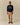 A man wearing a navy Paddington Cotton Text Sweater Navy with the white embroidered text Please look after this bear. Thank you., paired with tan trousers and brown boat shoes.