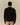 Back view of a person wearing a black Rowing Blazers x Paddington™ Paddington Tuxedo Wool Sweater over a white collared shirt and tan trousers.