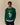 A person wears a dark green Rowing Blazers x Babar Babar Jardinier Cashmere Sweater featuring an intarsia elephant wearing a yellow hat and holding a red watering can, with the text BABAR jardinier above the character.