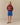 A person wearing a Jamie Cropped Button Snap Sheep Sherpa Red pullover, blue athletic shorts, and tan boat shoes.