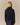 Back view of a person wearing an oversized navy Kaia Shawl Sweater Navy with a shawl collar over a plaid skirt.